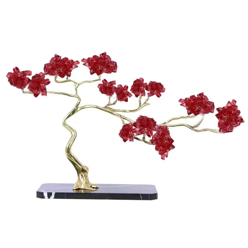 A metal decorative figurine featuring a sculpted bonsai tree with golden branches and red crystal blossoms on black marble