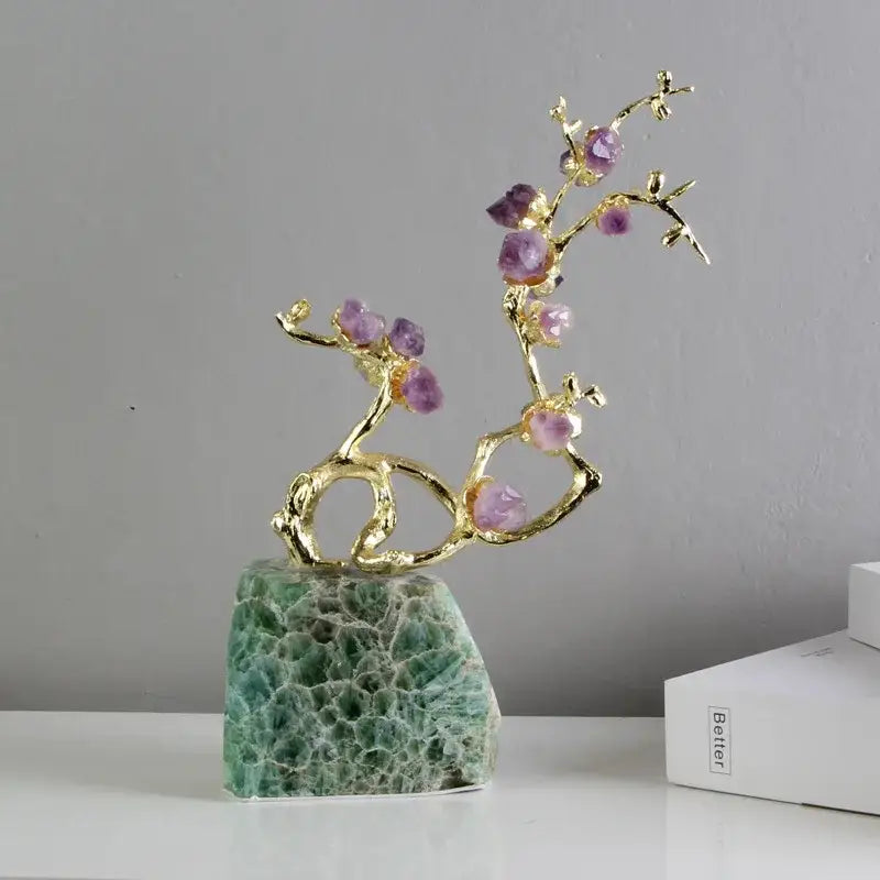 A delicate gold-toned brass tree ornament with faceted purple amethyst stones on green aventurine base