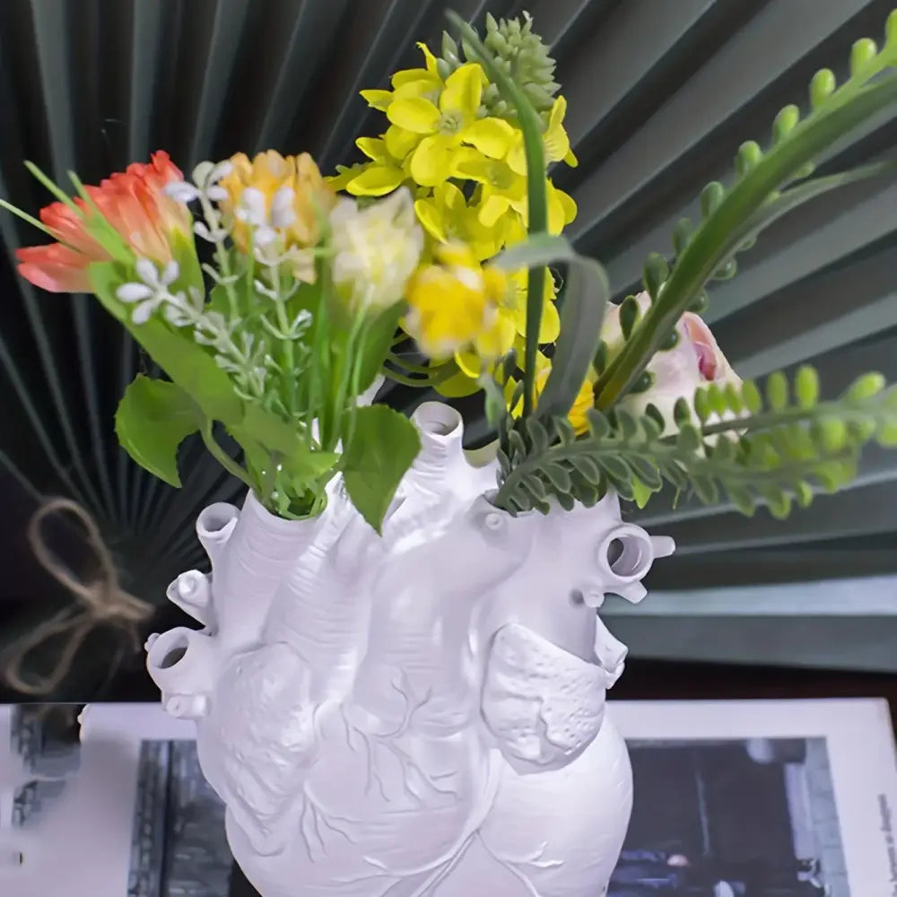 White anatomical heart resin vase by decorbites holding colorful artificial flowers as a decorative heart vase