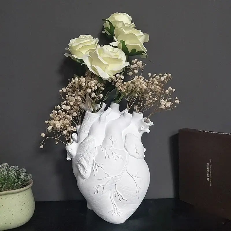 White ceramic anatomical heart shape vase holding cream roses and baby’s breath for living room decorbites heart shape decor