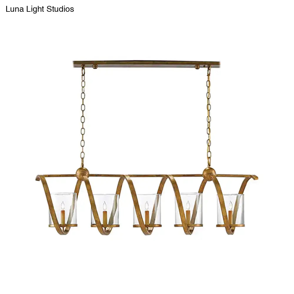 Gold-toned wrought iron chandelier with five clear glass candle holders and curved arms for dining room lighting in antique brass and aged silver tones