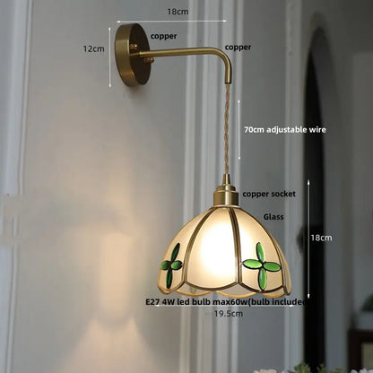 Antique brass wall light with decorbites amber glass stained shade featuring green clover motifs and warm lighting