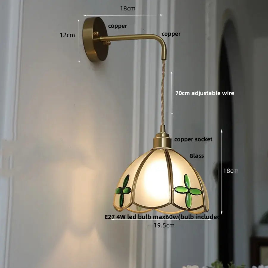 Antique brass wall light with decorbites amber glass stained shade featuring green clover motifs and warm lighting