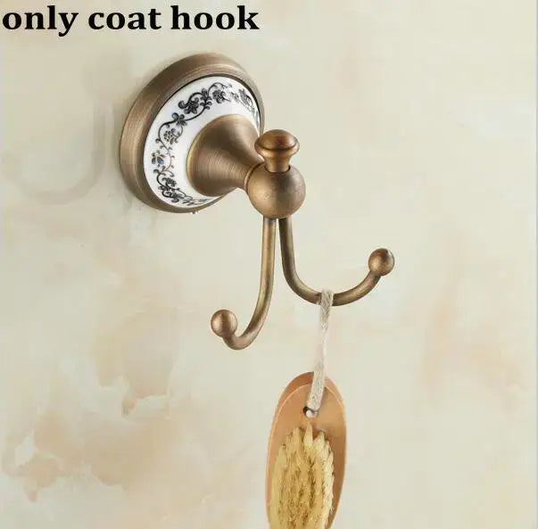 Antique brass coat hook with decorative white ceramic backplate and black floral patterns in decorbites bathroom accessories set