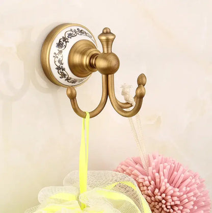 Antique brass double hook with ornate white ceramic backplate and black floral detailing from decorbites bathroom accessories set