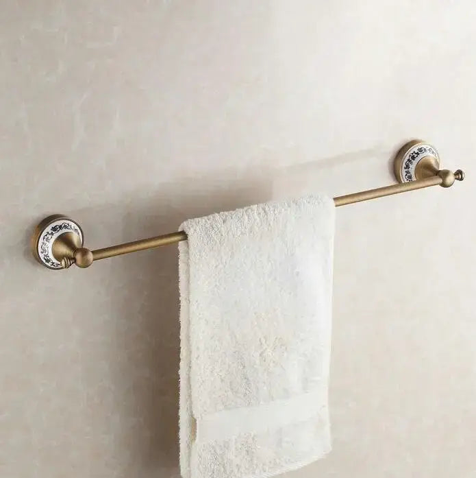 Antique brass towel rack with ornate ceramic ends holding white terry towel in decorbites bathroom accessories set