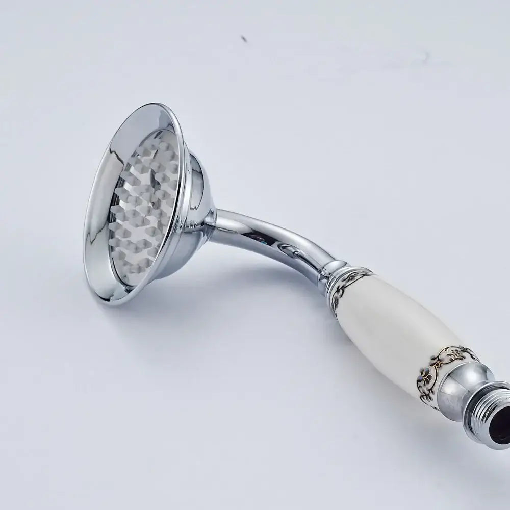 Antique brass and chrome hand shower head with chrome finish and cream ceramic handle featuring silver floral detail