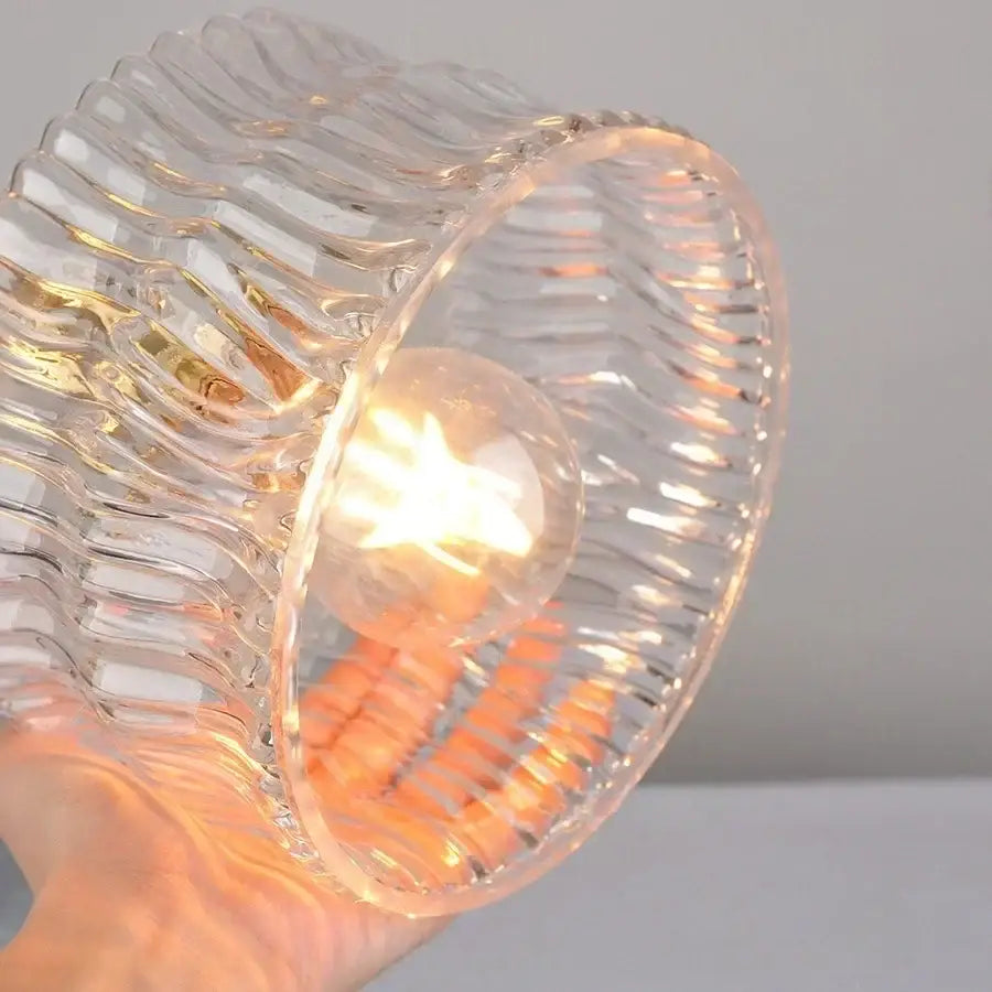 Antique brass wall sconce with clear glass wavy ribbed lampshade and warm-toned bulb decorbites clear glass lighting