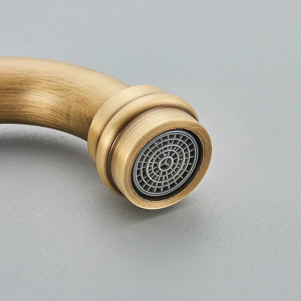 Antique brass and white ceramic basin waterfall faucet with a circular grid-patterned spray head kitchen tap