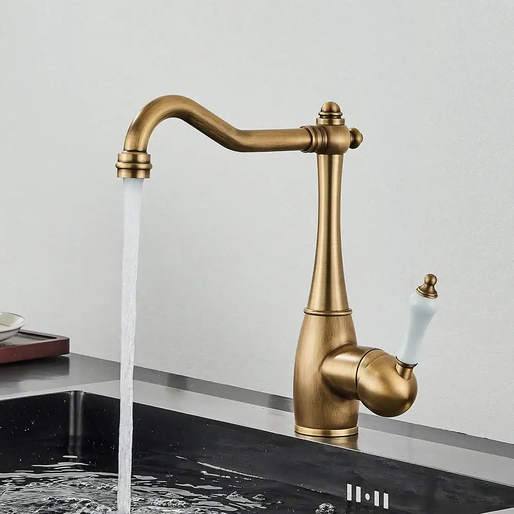 Antique brass basin waterfall faucet with white ceramic handle and elegant curved spout for kitchen use