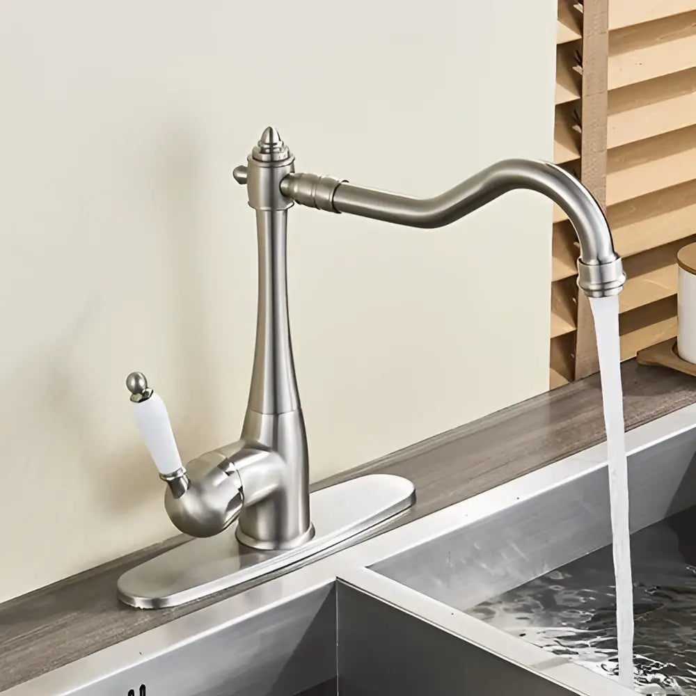 Antique brass basin waterfall faucet with a stainless steel curved spout and white ceramic handle for kitchen use