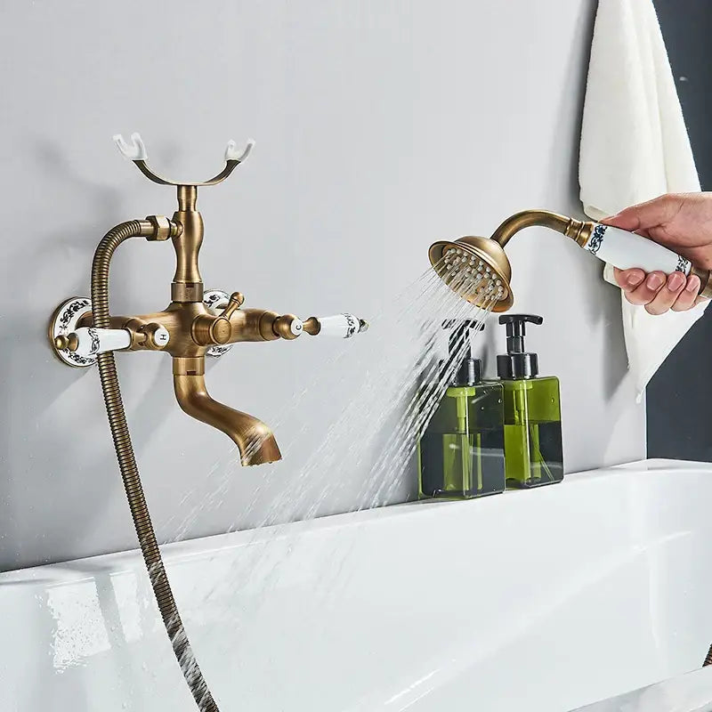 Antique brass and white ceramic bathtub shower faucet set featuring a faucet with ceramic handles and handheld showerhead