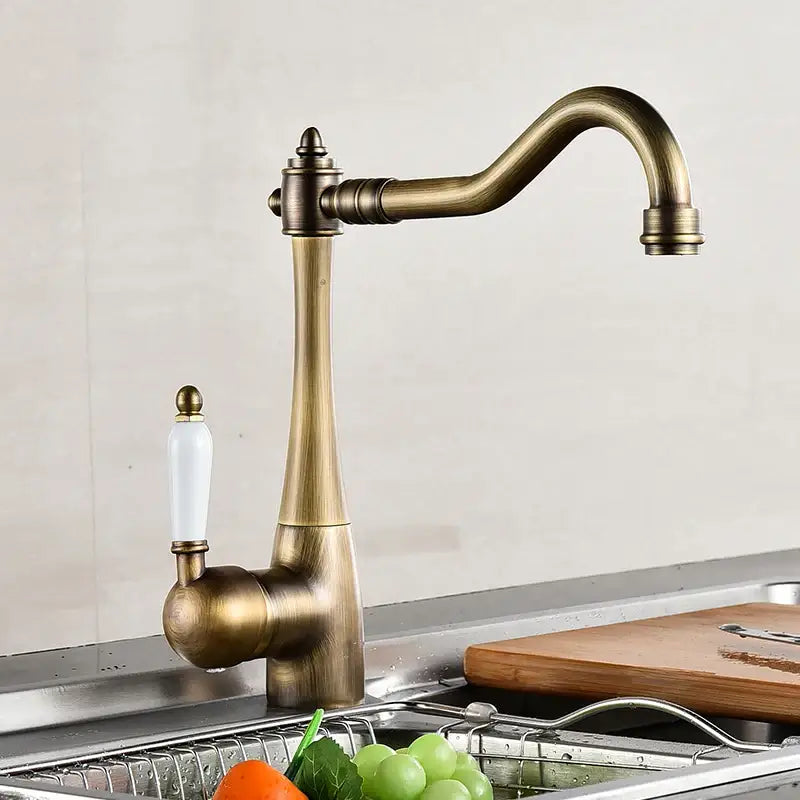 Antique brass and white ceramic kitchen faucet swivel mixer with an elegant curved spout and white ceramic handle