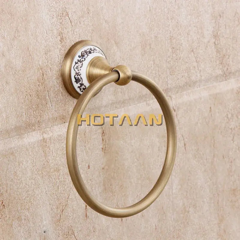 Antique brass towel ring with white ceramic backplate and black floral patterns in decorbites brass bathroom set
