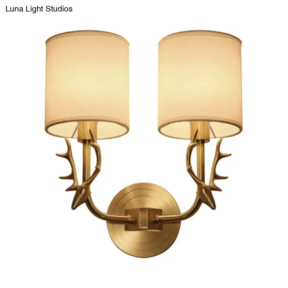 Antique brass antler wall sconce with fabric shade featuring a stylish design and two beige cylindrical shades for bedroom light