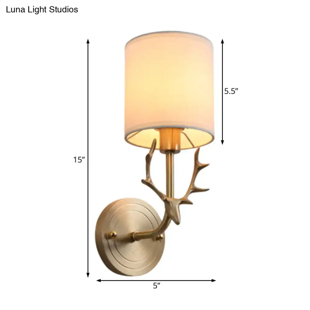 Antique brass antler wall sconce with cream fabric shade featuring a stylish design for bedroom lighting