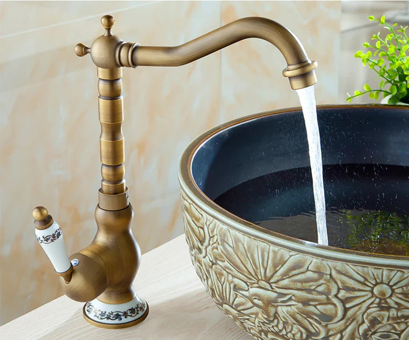 Antique brass basin faucet featuring ornate detailing with white ceramic handle accents for bathroom sinks