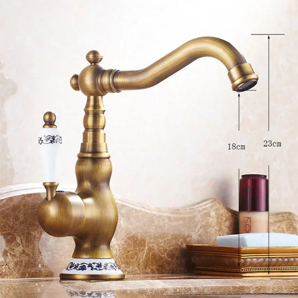 Antique brass basin faucet with ornate detailing and white ceramic handle featuring black floral patterns for kitchen use