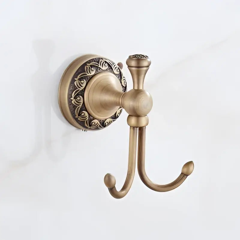 Antique brass bath hardware set featuring a double hook with ornate floral detailing in brass antique finish