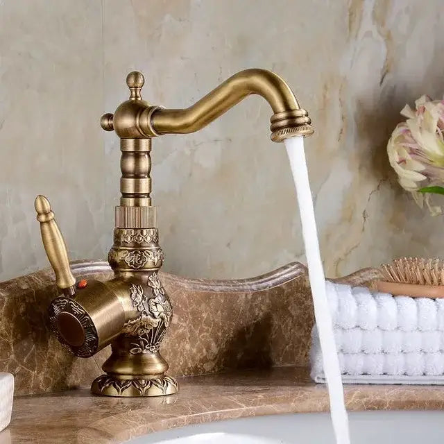 Antique brass bath hardware set featuring a brass antique faucet with ornate floral engravings and curved spout for bathroom decorbites