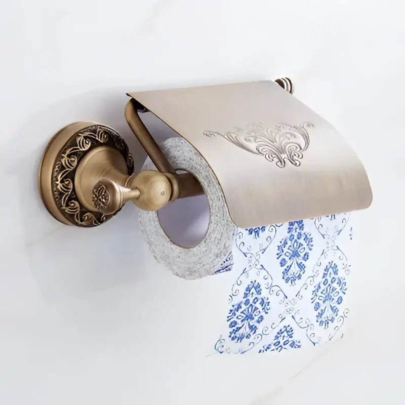 Antique brass bath hardware set featuring an ornate brass antique toilet paper holder with embossed floral cover