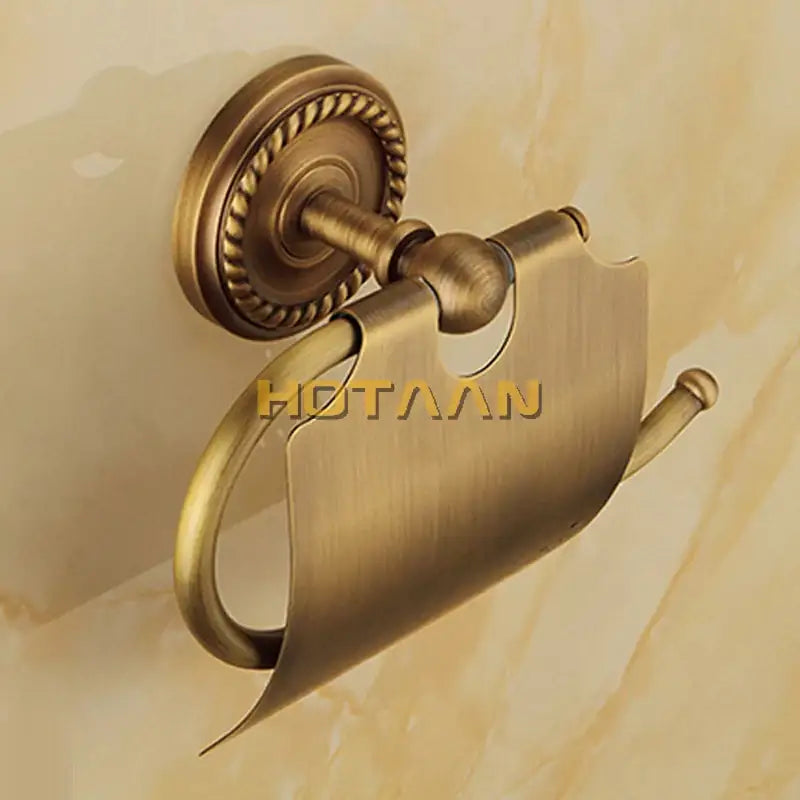 Antique brass-finished toilet paper holder with rope detail base and sleek curved design in brass bathroom accessories set