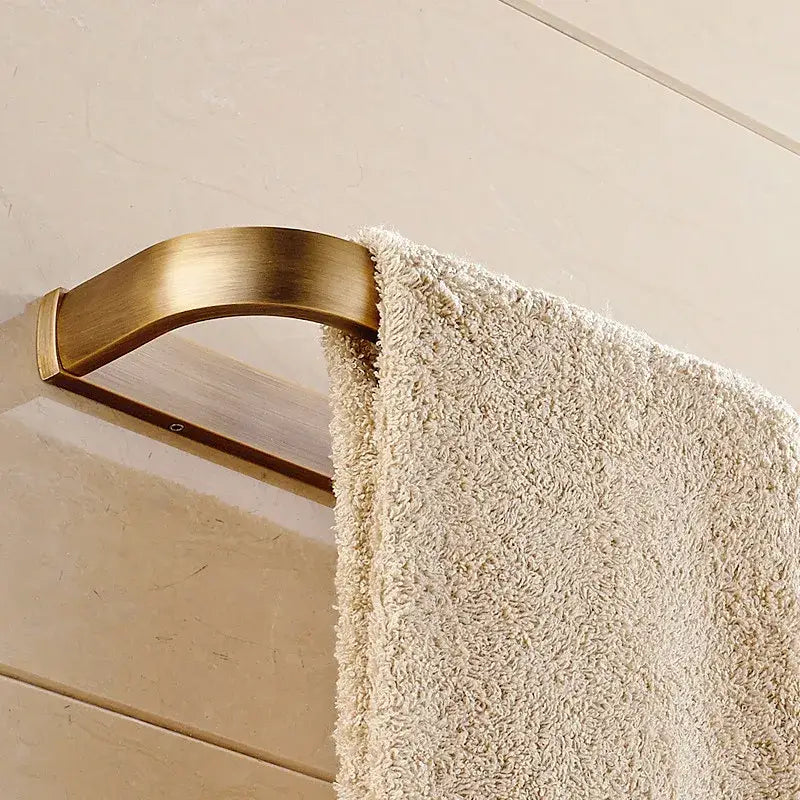 A plush off-white towel hangs on a sleek antique brass towel rack from decorbites bathroom accessories set
