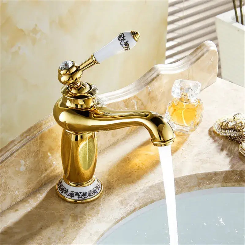 Antique brass bathroom basin water mixer with gold finish and white ceramic handle with black floral patterns and crystal accent