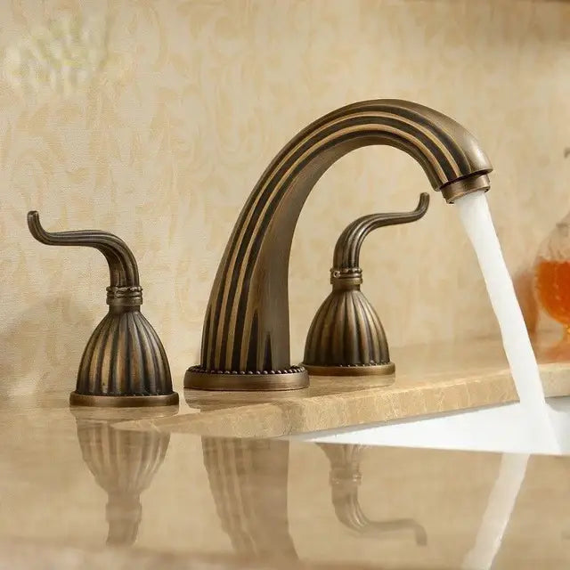 Antique brass bathroom faucet set with three ornate fluted handles and arched spout in brass bathroom faucet design