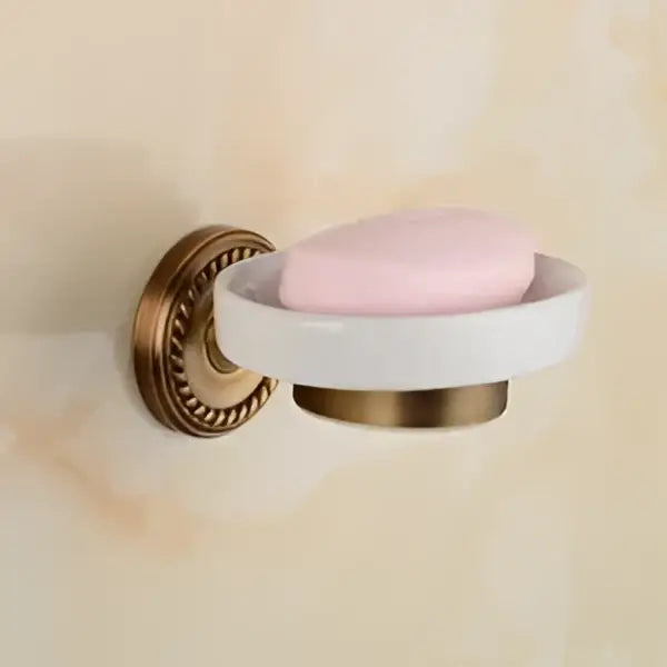 Antique brass wall-mounted soap dish holding pale pink soap from decorbites brass bathroom set with ornate mounts