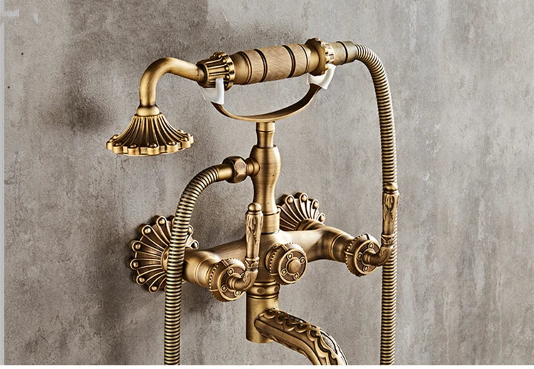 Antique brass bathtub shower set featuring wall-mounted vintage-style faucet with ornate fluted detailing and two hoses