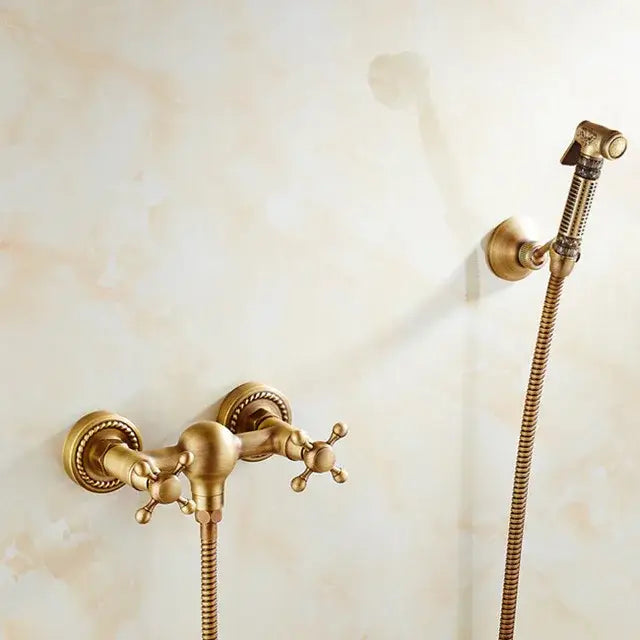 Antique brass bidet mixer faucet with ornate cross handles and matching handheld showerhead in brass finish