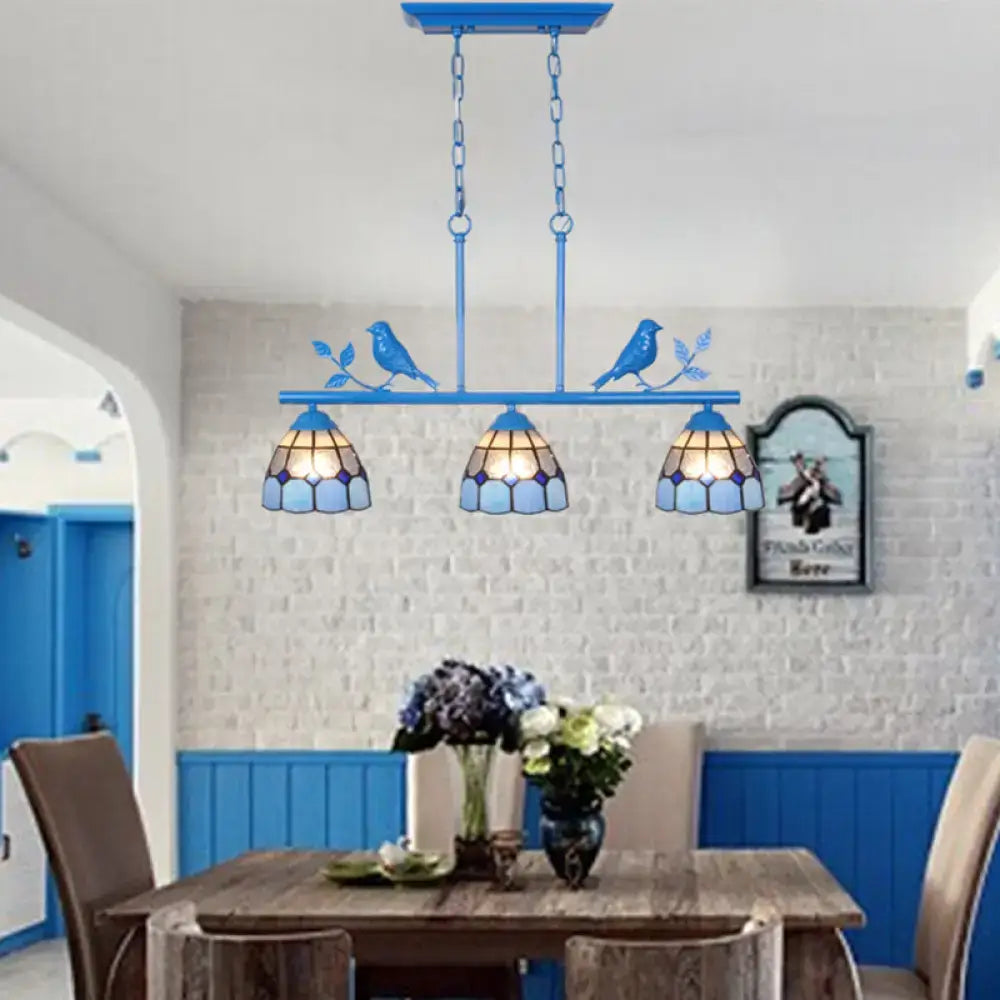 Blue tiffany-style indoor island pendant with three stained glass shades and bird motifs in antique brass finish