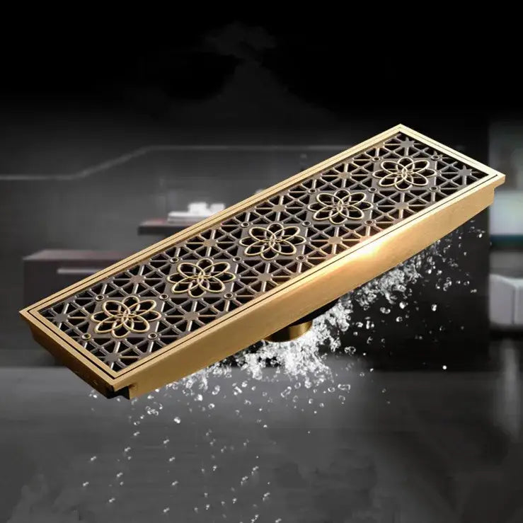 Antique brass gold-toned rectangular floor drain cover with intricate floral and geometric carved patterns for bathroom use