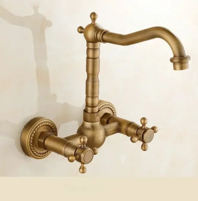 Antique brass ceramic wall mount faucet with ornate cross handles and decorative rope detailing for kitchen use