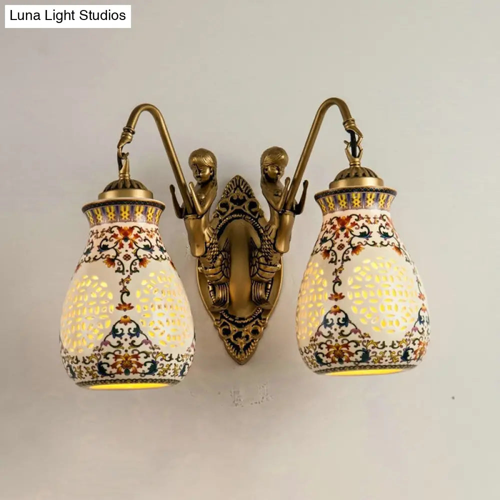 Aplique de pared de latón antiguo con cerámica, jarrón perforado, diseño tradicional y pequeño detalle de sirena.