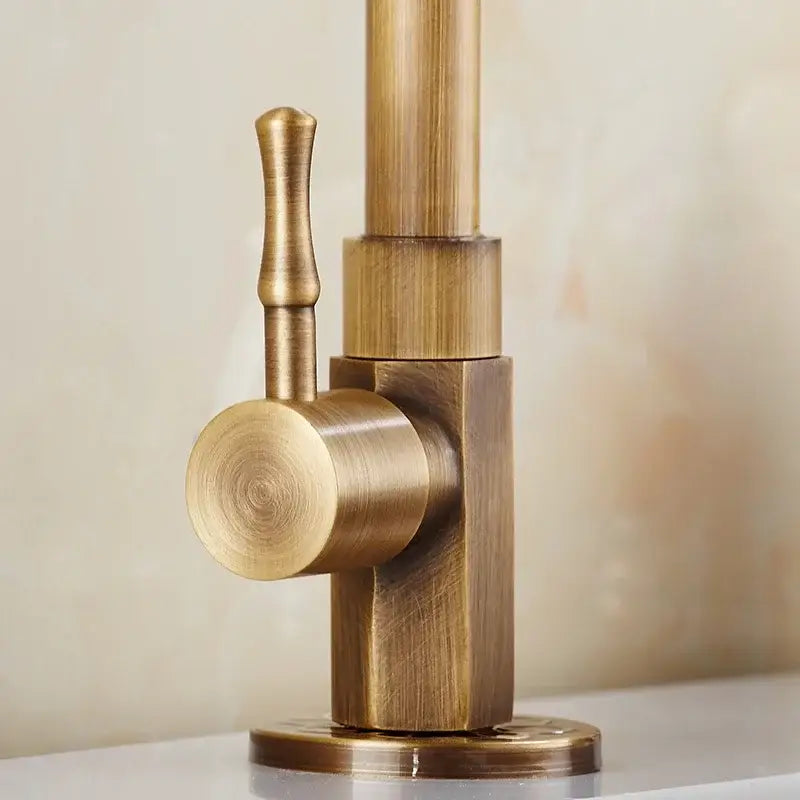 Antique brass classic cold water kitchen faucet with curved cylindrical spout and round textured handle in brass finish