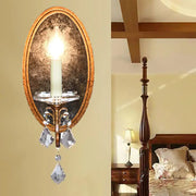 Antique brass oval wall sconce with clear crystal droplets and candle-style bulb for bedroom candle light