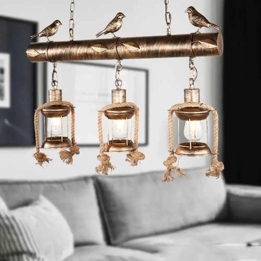 DecorBites antique brass lantern pendant with three clear glass lights, bird accent, and bulb base in rustic coastal style