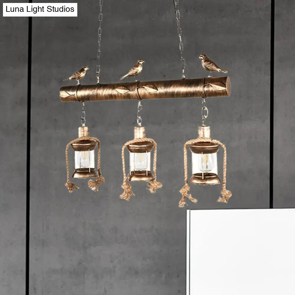 Decorbites antique brass pendant with three clear glass lanterns and bulb base suspended by rope and wooden beam with bird accents