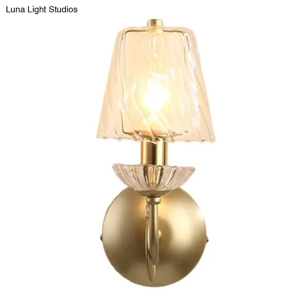 Gold-finished conical sconce light with clear twisted glass shade and crystal petal accent for bedroom lighting