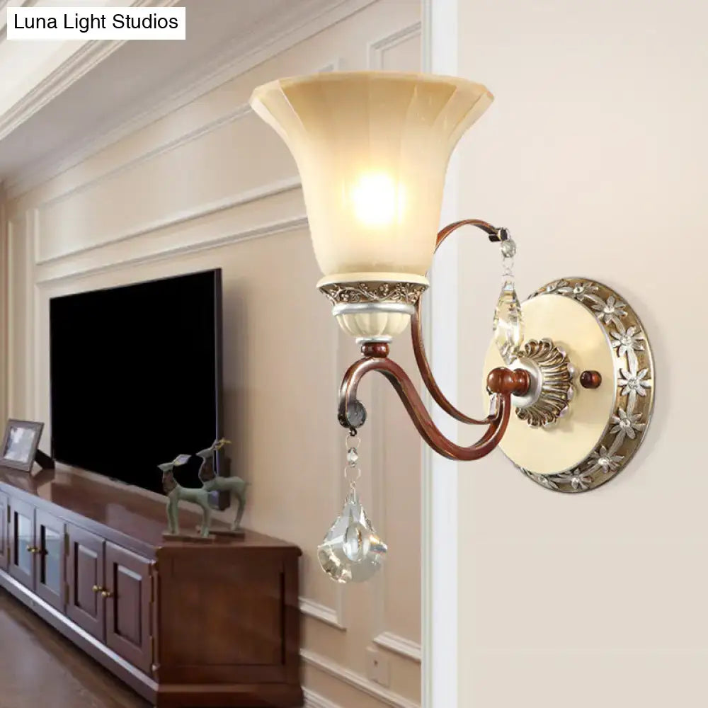 Antique brass bell wall sconce with cream fluted glass shade and crystal droplets for lodge style bedroom lighting