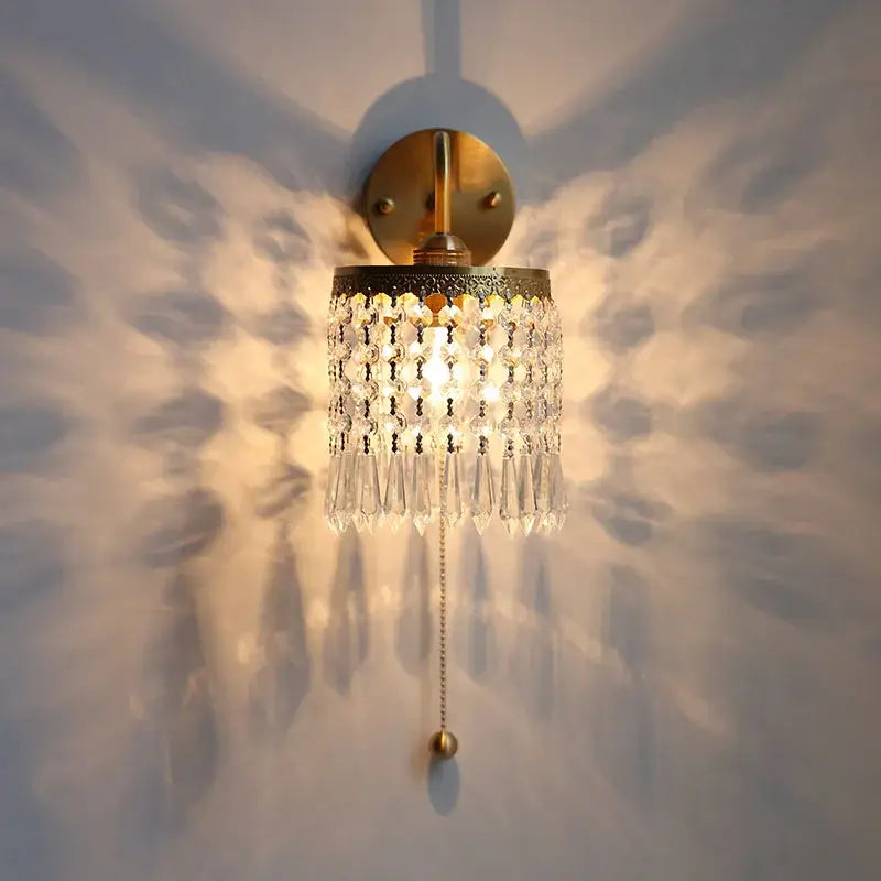 Antique brass crystal led wall sconce with gold-toned finish and cascading clear crystal droplets with pull chain