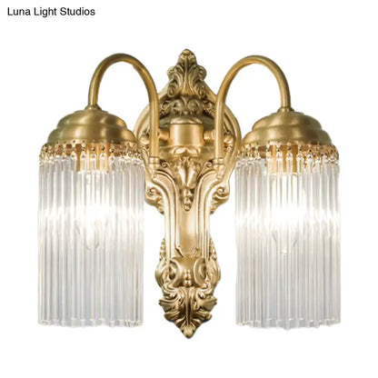 Antique brass two-light wall sconce with ornate scrollwork and vertical crystal rod prisms for corridor lighting