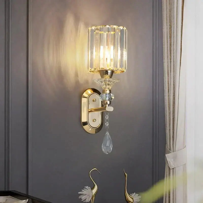 Gold-finished wall lamp with cylindrical crystal shade and teardrop pendant from decorbites crystal led wall collection