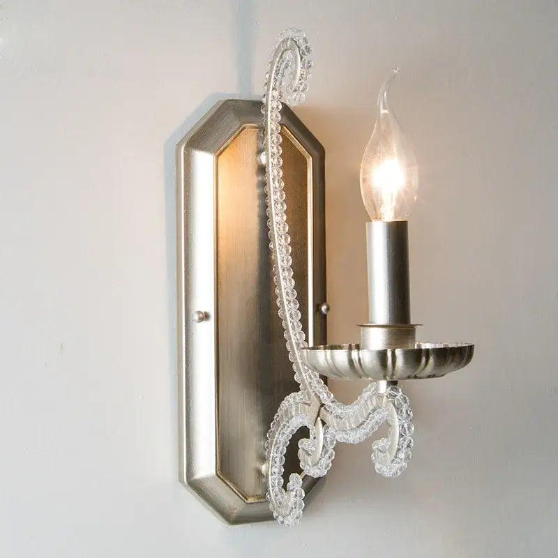 A silver-toned wall sconce with decorative clear glass beaded arm in an antique brass decorbites crystal led chandelier design