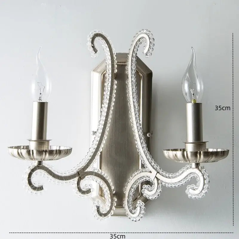 Silver-toned decorbites crystal led wall sconce with ornate crystal-encrusted arms and two candle-style bulbs for living room lighting