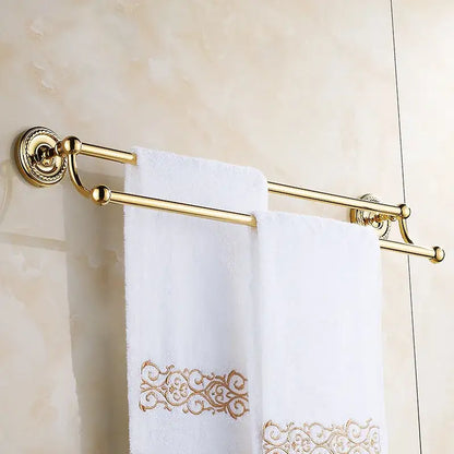 Antique brass double towel bar with gold-finished ornate circular mounts holding white towels with gold embroidery