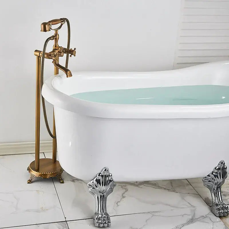 White claw-foot bathtub with decorbites brass floor dual handle bath set featuring gold-toned faucet and silver feet