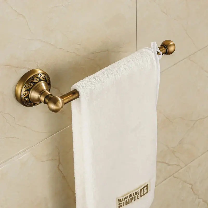Antique brass floral engraved double towel rack with ornate detailing holding white terry cloth towel bathroom hardware set